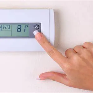 Hand adjusting a digital wall thermostat