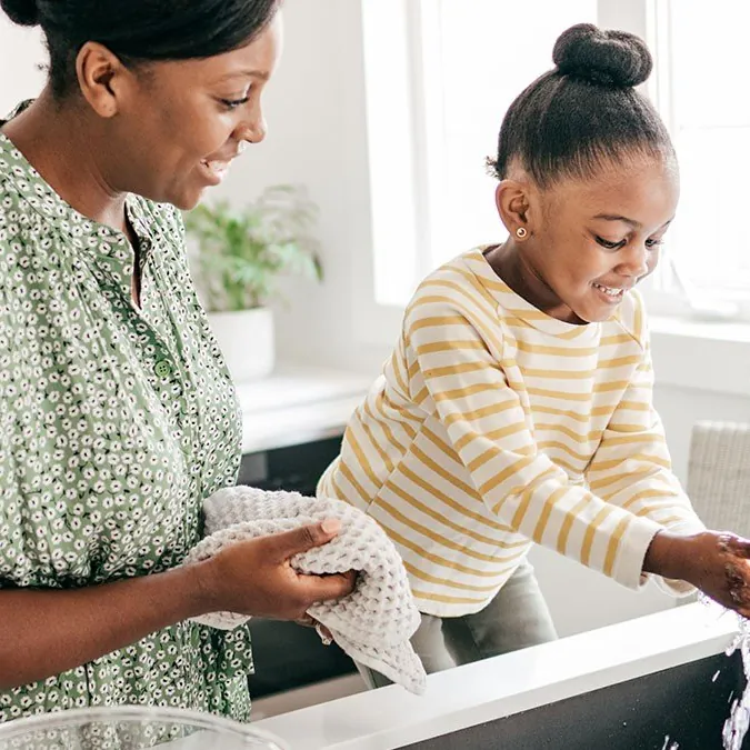 Mother and daughter washing hands at a kitchen tap