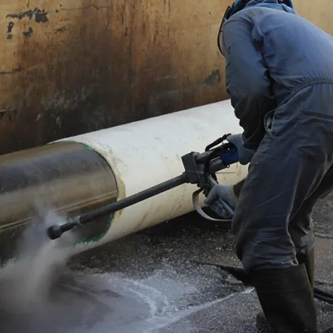 Worker cleaning a large pipe with a high-pressure water jet