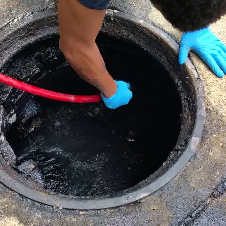 Worker feeding a hose into a sewer access