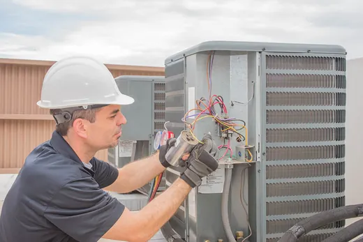Technician checking the wiring inside an outdoor unit