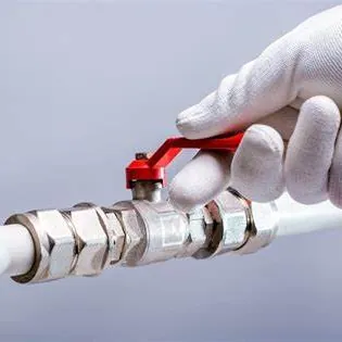 Gloved hand on a valve fitted to a white water pipe